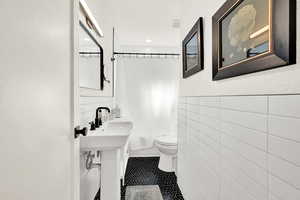 Bathroom with tile walls, toilet, and tile patterned floors