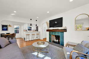 Living room featuring a wealth of natural light, ornamental molding, wood-type flooring, and a tile fireplace