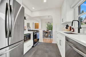 Kitchen with pendant lighting, white cabinets, stainless steel appliances, and dark hardwood / wood-style flooring