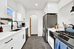 Kitchen with appliances with stainless steel finishes, sink, hanging light fixtures, white cabinets, and decorative backsplash