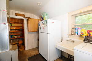 Kitchen featuring washer / dryer, lofted ceiling, and white refrigerator