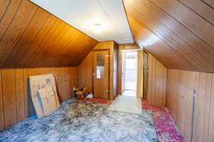 Additional living space featuring vaulted ceiling, wood ceiling, carpet floors, and wood walls