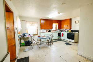 Kitchen with a textured ceiling and white appliances