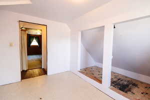 Spare room featuring wood-type flooring and vaulted ceiling