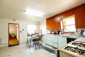 Kitchen with a textured ceiling, white appliances, and plenty of natural light