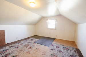 Additional living space featuring hardwood / wood-style floors and vaulted ceiling