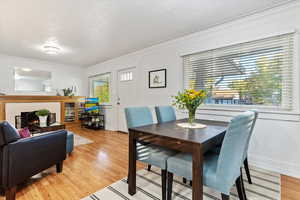 Dining room with crown molding, a textured ceiling, light hardwood / wood-style floors, and plenty of natural light