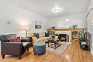 Living room with a tiled fireplace, crown molding, a textured ceiling, and light wood-type flooring