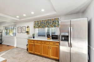 Kitchen with light hardwood / wood-style floors, a raised ceiling, appliances with stainless steel finishes, and crown molding