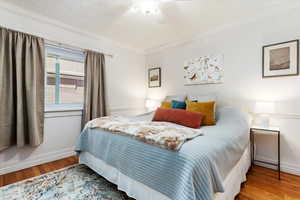 Bedroom with crown molding, hardwood / wood-style flooring, and ceiling fan