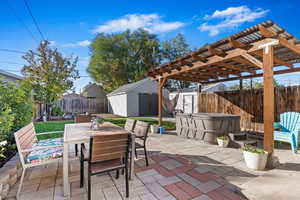 View of patio featuring a shed, a hot tub, and a pergola