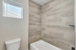 Bathroom with tiled shower / bath and toilet