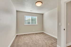 Bedroom 2: Carpeted spare room with a textured ceiling