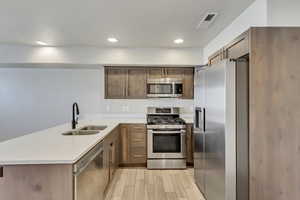 Kitchen with quartz countertops, appliances with stainless steel finishes, light hardwood / wood-style flooring