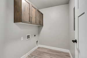 Laundry area with hookup for a washing machine, light hardwood / wood-style flooring, electric dryer hookup, and cabinets