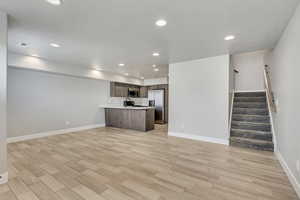 Unfurnished living room with sink and light wood-type flooring