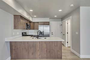 Kitchen featuring sink, stainless steel appliances, light hardwood / wood-style flooring, and kitchen peninsula