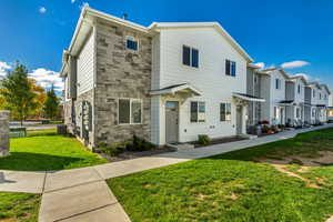 View of front of the end-unit townhome, featuring a front lawn and central AC unit