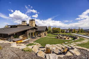 Back of property with a lawn, a patio area, and an outdoor fire pit