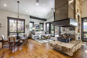 Living room featuring hardwood / wood-style flooring, a fireplace, high vaulted ceiling, and a chandelier