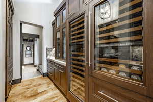 Wine room with wine cooler and light hardwood / wood-style floors