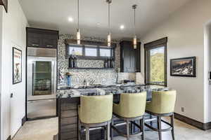 Kitchen with a center island, backsplash, oven, vaulted ceiling, and a kitchen bar