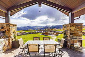 View of patio / terrace featuring an outdoor stone fireplace and a mountain view