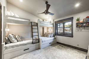 Carpeted bedroom featuring ceiling fan and vaulted ceiling