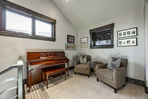 Sitting room with light colored carpet and vaulted ceiling