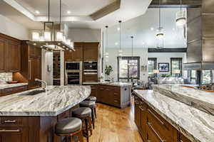 Kitchen featuring a kitchen breakfast bar, light stone counters, light hardwood / wood-style flooring, a spacious island, and decorative light fixtures