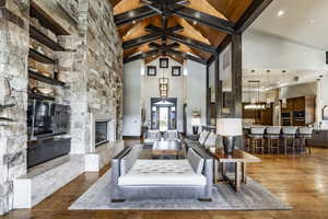 Living room featuring a fireplace, hardwood / wood-style flooring, high vaulted ceiling, and a notable chandelier