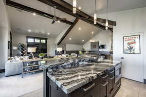 Kitchen featuring beam ceiling, a large island, high vaulted ceiling, light hardwood / wood-style floors, and decorative light fixtures