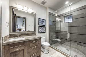 Bathroom with tile patterned floors, vanity, toilet, and a shower with door