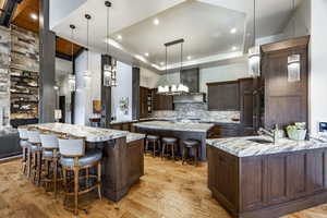 Kitchen featuring a breakfast bar area, light stone countertops, decorative light fixtures, and light wood-type flooring