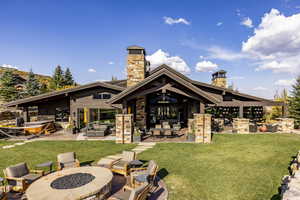 Back of property with an outdoor living space with a fireplace, a yard, and a patio area