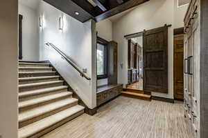 Foyer featuring beamed ceiling, a barn door, and light hardwood / wood-style flooring