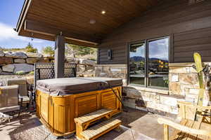 View of patio with a mountain view and a hot tub