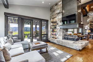 Living room with a mountain view, light hardwood / wood-style floors, high vaulted ceiling, and a stone fireplace