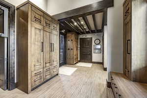 Corridor with beam ceiling and light wood-type flooring