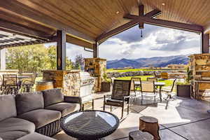 View of patio featuring an outdoor living space with a fireplace, area for grilling, a mountain view, and an outdoor kitchen