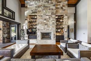 Living room with light hardwood / wood-style floors, a towering ceiling, a fireplace, and wood ceiling