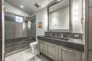 Bathroom with vanity, lofted ceiling, toilet, tasteful backsplash, and a shower with shower door