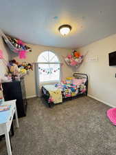 Bedroom with dark colored carpet and a textured ceiling