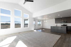 Living room featuring a mountain view, ceiling fan with notable chandelier, plenty of natural light, and dark hardwood / wood-style floors