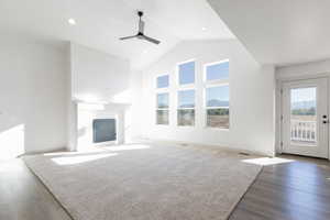 Unfurnished living room featuring ceiling fan, high vaulted ceiling, and dark hardwood / wood-style floors