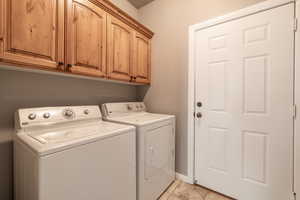 Laundry area with cabinets, light tile patterned flooring, and washing machine and dryer