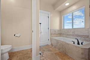 Bathroom featuring toilet and tiled tub