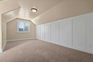 Bonus room featuring vaulted ceiling and carpet flooring