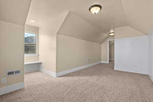 Bonus room featuring lofted ceiling and light carpet