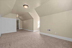 Additional living space with carpet flooring and vaulted ceiling